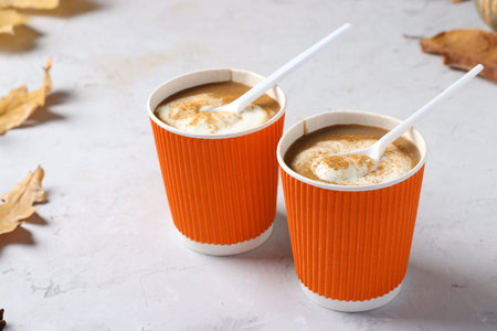 Paper cups with tasty pumpkin latte and spice on gray table. Closeup. Horizontal format