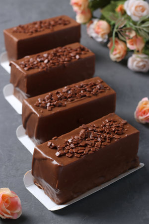 Four mousse desserts covered with chocolate on a dark gray background. Closeup. Vertical formatの写真素材
