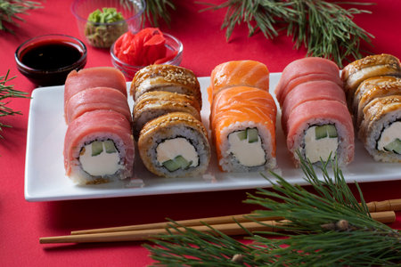 Festive Christmas dinner with salmon, tuna and eel sushi set with philadelphia cheese on white plate on red background. New Year party.の写真素材