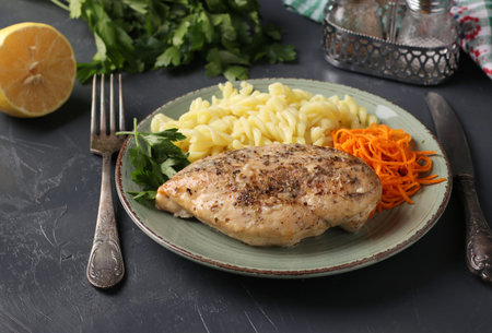 Baked chicken fillet, pasta and fresh carrots - a delicious and healthy breakfast. Close-upの写真素材