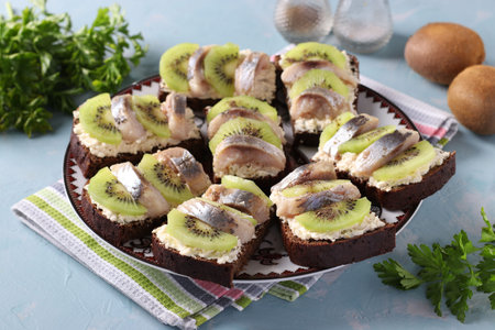 Homemade sandwiches with kiwi, herring, cream cheese and garlic on a light blue background....