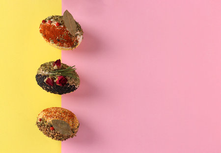 Easter concept with eggs decorated with different spices and cereals without dyes and preservatives on pink and yellow background. Copy spaceの写真素材