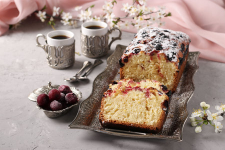 Homemade cupcake with cherries on a metal tray on a light gray background, and two cups of coffee....