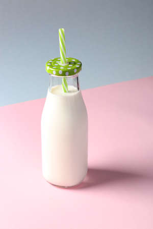 Milk bottle on pink and blue creative background. Vertical formatの写真素材