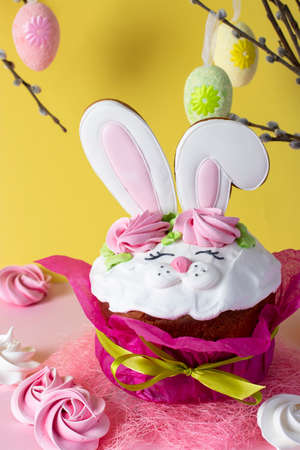 Easter cupcake decorated with bunny ears on a yellow background. Spring church holiday concept. Vertical formatの写真素材
