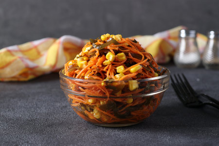 Salad with kelp, carrots and corn in a transparent bowl on a dark gray background. Healthy eatingの写真素材