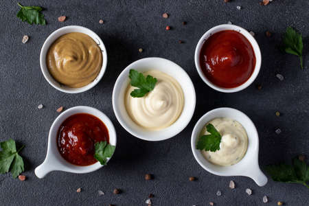 Set of sauces - ketchup, mayonnaise, mustard, barbecue sauce and tartar on dark gray background. Top viewの写真素材