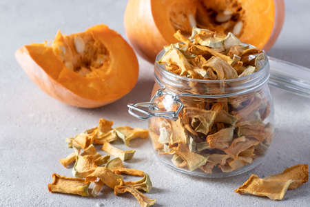 Homemade pumpkin chips in a glass jar on a light gray background. Close-upの写真素材