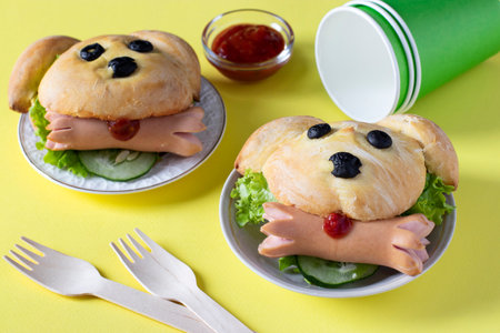 Sandwiches in the shape of a dog with a sausage on yellow background. Cooking idea for kids. Closeupの写真素材