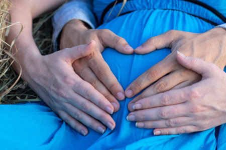 Pregnant woman with her husband hands on her stomach, concept of waiting for a child, young parents,...