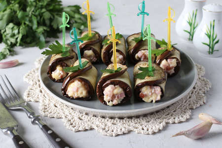 Eggplant rolls with ham and cheese on a plate on light gray background.の写真素材