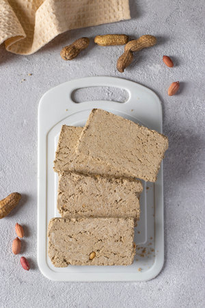 Sweet sunflower halva with peanut on white board on light gray background. Top view