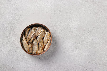 Baltic sprats in an tin can on a light gray background. View from above