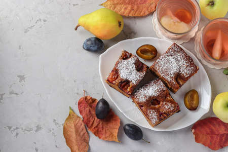 Sliced autumn pie with plums and compote on a gray table. Autumn still life. View from aboveの写真素材