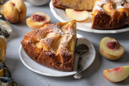 Sliced peach pie sprinkled with powdered sugar on light gray table. Close-upの写真素材