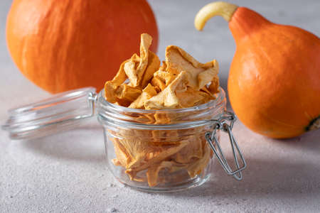 Homemade pumpkin chips in a glass jar on a light gray background.の写真素材