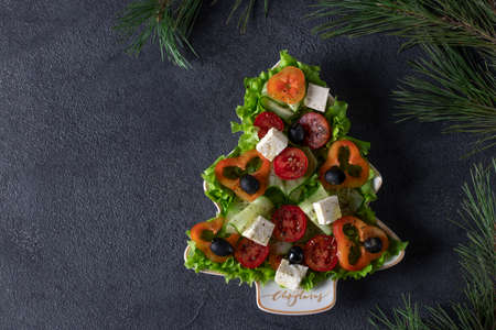 Healthy Greek salad served in plate as Christmas tree with festive decoration on dark background. Top view. Copy spaceの写真素材