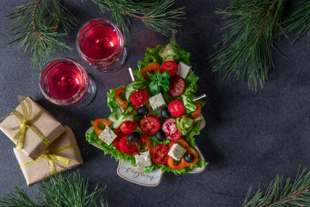 Festive canapes with cucumbers, tomatoes and cheese served in plate as Christmas tree, on dark gray background with two glasses of wine. Top viewの写真素材