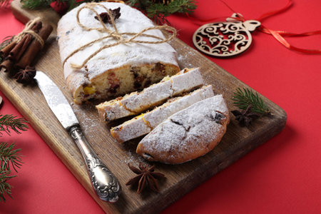 Christmas tasty stollen with dry fruits, berries and nuts on red background. Traditional German...