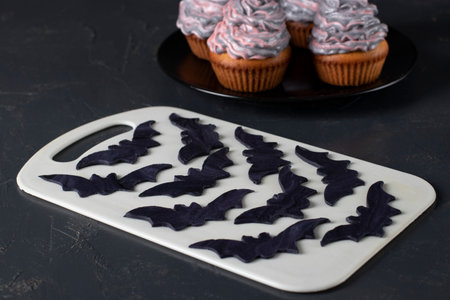 Cooking figures of bats from black mastic for decorating cupcakes for Halloween party. Closeup