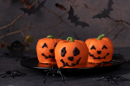 Dessert for Halloween - sweet pumpkin-shaped mousse cakes on a dark background with a decor of...
