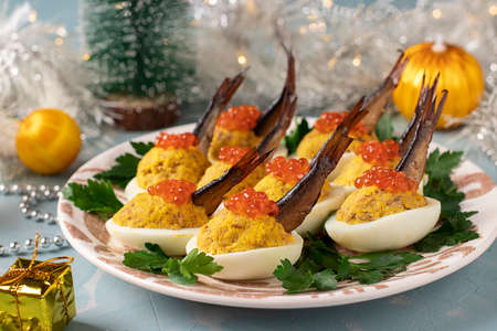 Delicious festive snack - Eggs stuffed with sprats and red caviar on a plate on New year blue background.の写真素材