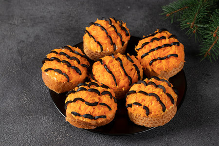 Tiger canapes for New Year 2022 of salted herring, carrot and black olives on croutons of white...