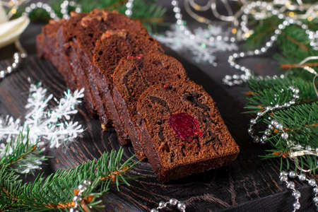 Sliced christmas cupcake with cherries and chocolate covered with chocolate icing on wooden board on new year background, Close-upの写真素材
