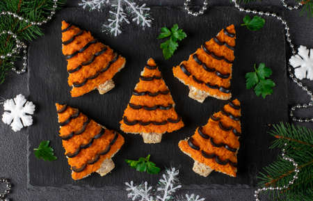Sandwiches in shaped of christmas tree for New Year Tiger 2022 of carrot, cheese and black olives on white bread on dark gray board, Top viewの写真素材