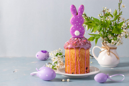 Easter cake with gingerbread in shape of rabbit, as well as colorful eggs on a blue background,...