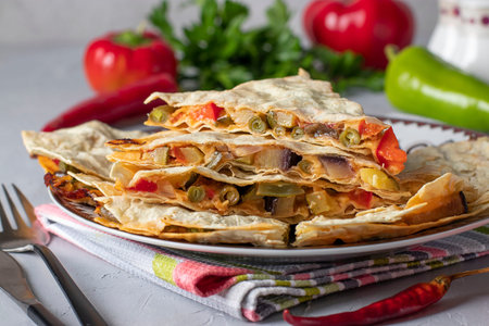 Mexican tortilla quesadilla appetizer with vegetables and cheese in plate on light background