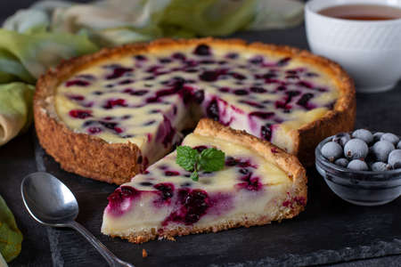 Homemade open black currant shortbread pie on a slate plate on dark gray backgroundの写真素材