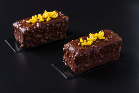 Two Chocolate Almond Brownie covered gourmet chocolate glaze on black background. Closeup