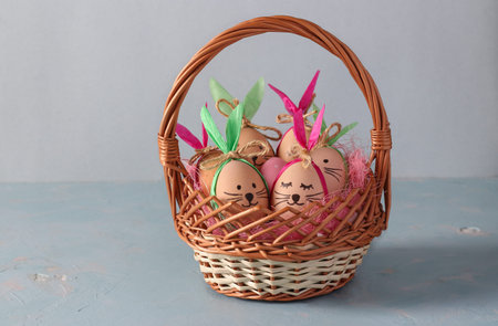 Easter bunnies made of eggs with multi-colored ears made of colored paper lokated in basket on a blue backgroundの写真素材
