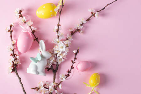 Blossoming tree branch, easter bunny, yellow and pink eggs on pink background, easter conceptの写真素材