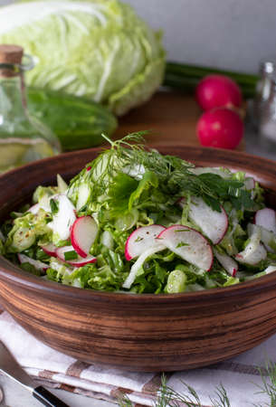 Salad with Chinese cabbage, cucumbers, radishes and chives, dressed with olive oil, Vertical formatの写真素材