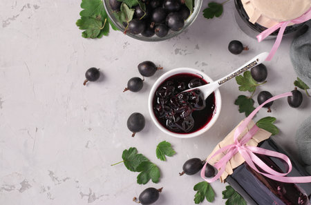 Homemade yoshta jam with whole berries, in bowl and glass jars on light gray background, Top viewの写真素材
