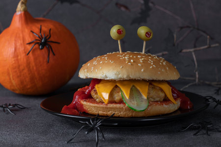 Funny monster chicken burger with toast cheese, ketchup, olives and cucumber. creative halloween foodの写真素材