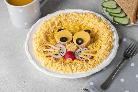 Fun food for kids breakfast - cute lion head made from scrambled eggs, cheese, radishes and black olives on white plate, Close-upの写真素材