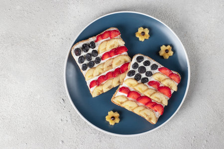 American flag sandwiches with fruit and cream cheese on rye bread on blue plate. Independence Day...