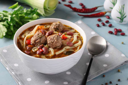 Asian spicy soup with meatballs, beans and noodles on white bowlの写真素材