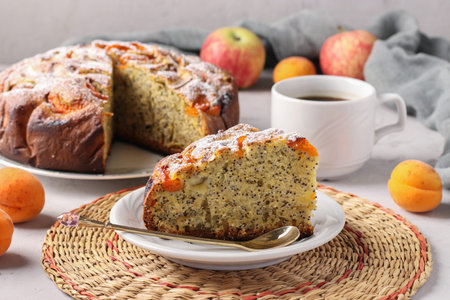 Homemade apricots pie with poppy seeds and apples, with cup of coffee on gray background