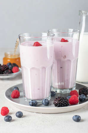 Smoothie from fresh berries, natural yogurt and honey in two tall glasses on gray backgroundの写真素材