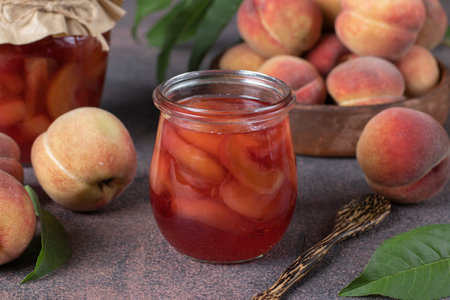 Homemade transparent peach jam in open glass jar on brown background, Close-upの写真素材