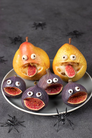 Spooky pear and fig monsters for Halloween party on gray background decorated with spiders and bats, Vertical imageの写真素材