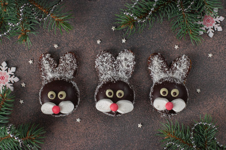 Rabbits made of cookies, chocolate, marshmallows and coconut flakes on brown background. Christmas...