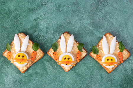 Sandwiches of canned tuna, eggs and melted cheese, decoration bunny from egg on green background,...