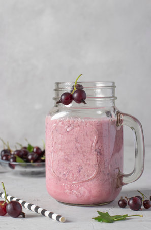 Natural yogurt and black currant smoothie in glass jar on light gray background, Vertical formatの写真素材