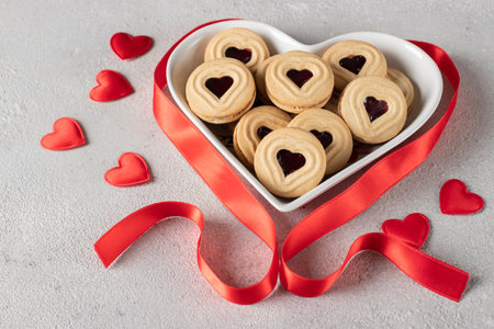 Homemade shortbread with raspberry jam heart-shaped filling on gray backgroundの写真素材
