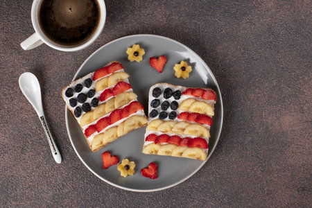 American flag sandwiches with fruit and cream cheese on rye bread and cup of coffee on gray plate. Independence Day breakfast idea. Top viewの写真素材